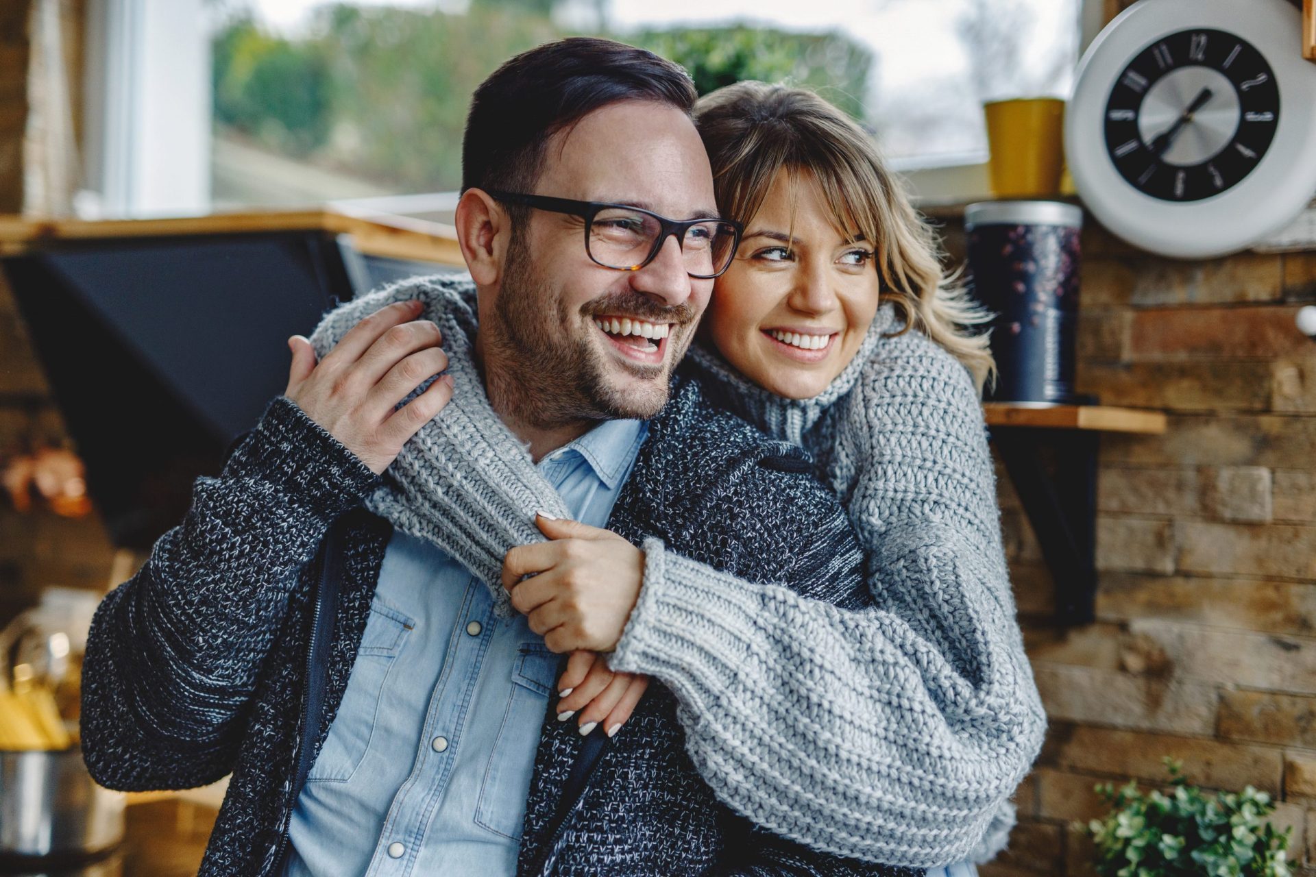 Portrait of happy couple in love embracing in the kitchen and looking away.
